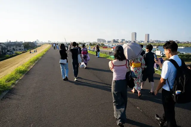 花火の会場へ江戸川の土手を歩く人たち