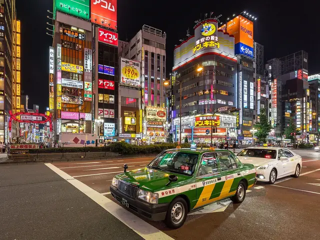 夜の新宿の大通りを走るタクシーとネオン