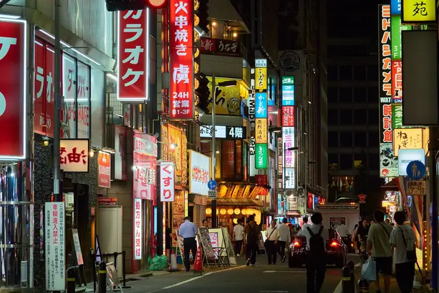 カラオケや飲食店の看板が並ぶ夜の新宿の通り