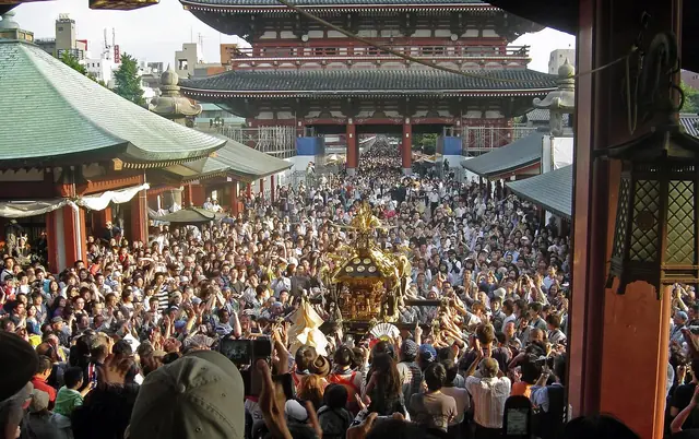 三社祭で人波の浅草寺境内を進む神輿