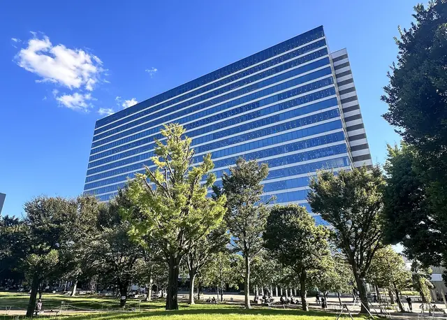 Осенние деревья на газоне парка Накано Сики-но-мори перед башней Nakano Central Park South