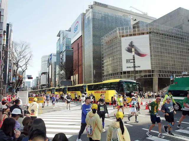 銀座・数寄屋橋交差点を走る東京マラソンのランナーと沿道の観客