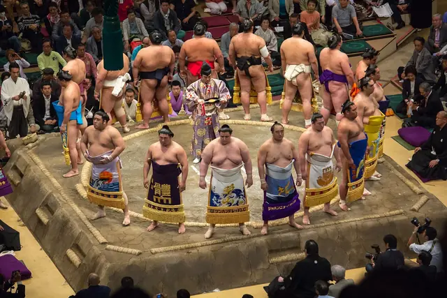 Wrestlers in decorated aprons stand around the ring for the entering ceremony at the May sumo tournament