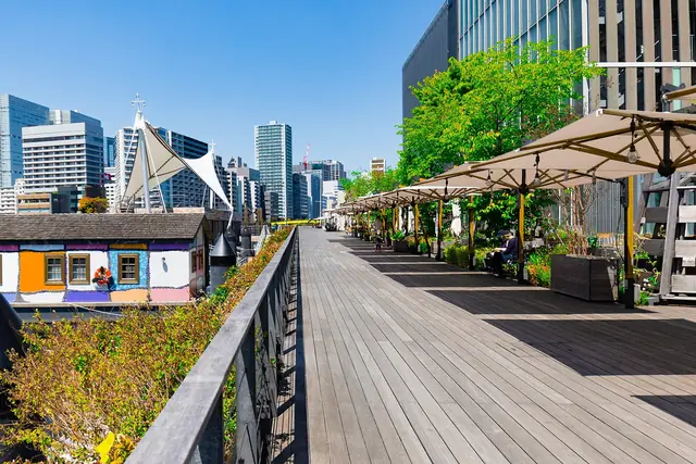 The wooden boardwalk with cafe parasols along the canal at Tennozu Isle