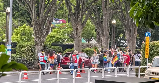 Участники шествия Tokyo Pride с радужными флагами идут по улице Сибуя