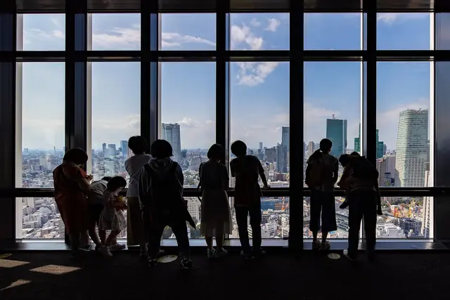 メインデッキの大きな窓から東京を眺める人々のシルエット
