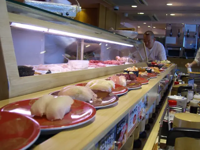 東京の回転寿司店でレーンを回る握り寿司の皿