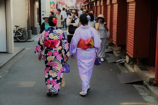 赤いシャッターが並ぶ東京の路地を歩く浴衣姿の二人